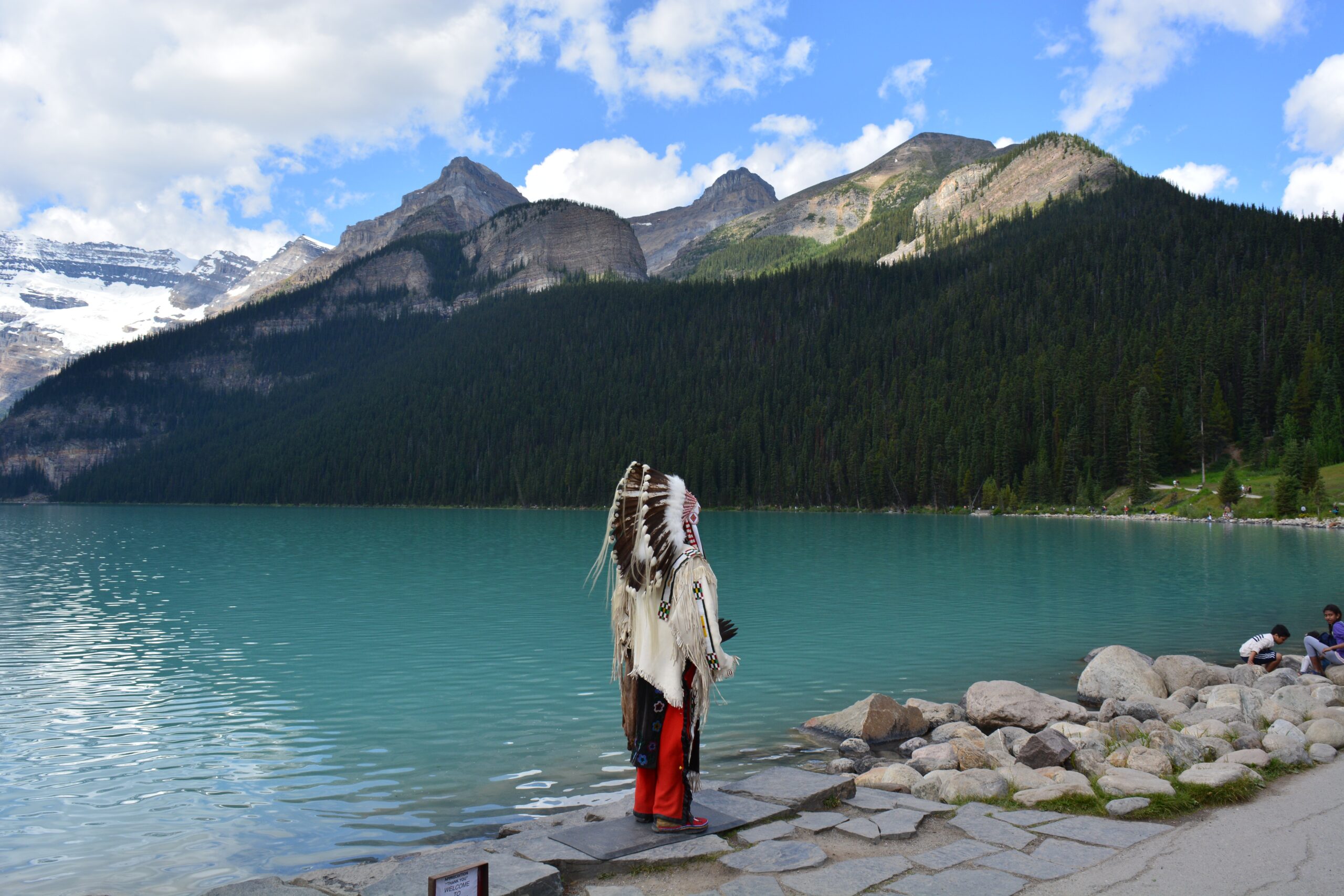 Native American standing near shore looking at mountains